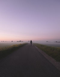 Rear view of man walking on road against sky