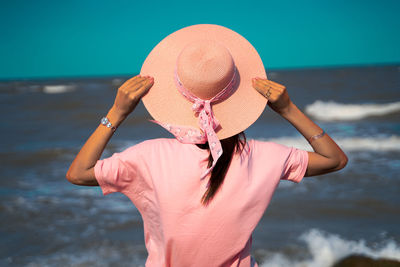 Midsection of woman wearing hat while standing on beach