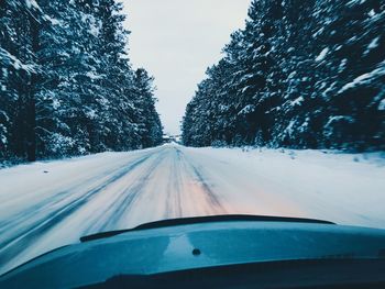 Snow covered road seen through car windshield during winter