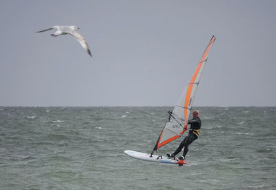 Low angle view of man flying over sea against sky