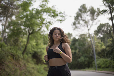 Portrait of young woman standing against trees