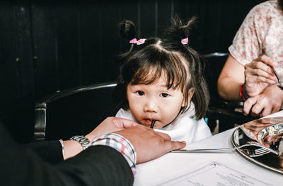 Portrait of cute girl sitting on table at home