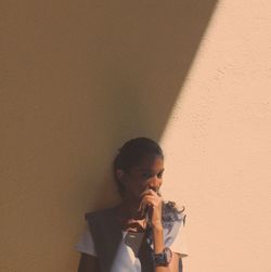 Portrait of young woman standing against wall