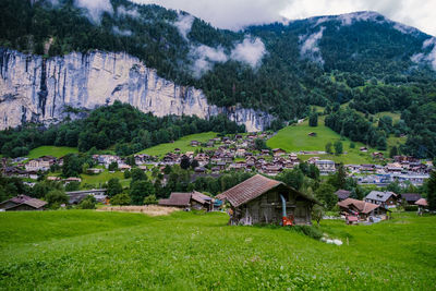 Houses on field by buildings against mountains