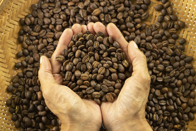 Cropped hand holding roasted coffee beans