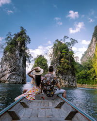 Rear view of couple sitting in boat on sea