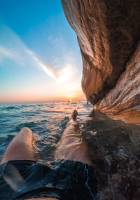 A man lies in the water under white rocks in abkhazia at sunset