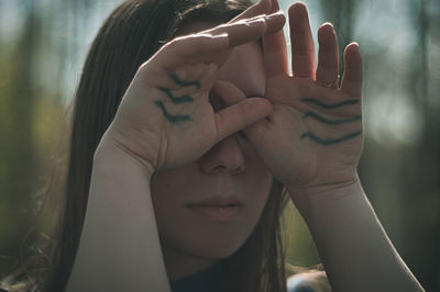 Close-up of young woman covering eyes with hands