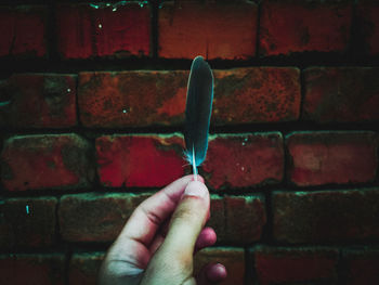 Close-up of human hand against brick wall
