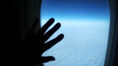 Close-up of silhouette hand against blue sky