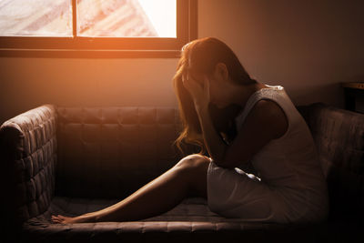 Young woman sitting on sofa at home