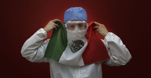 Portrait of man with protective workwear covering mouth with flag