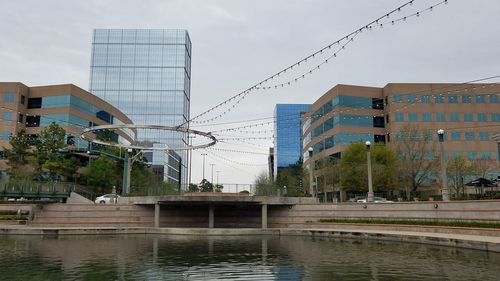 Buildings by river against sky in city