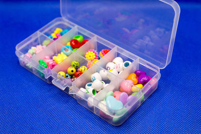 Plastic container with colored round buttons, jewelry clothes in separate cells.