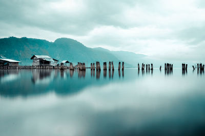 Panoramic view of wooden posts in lake against sky