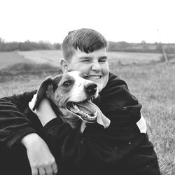 Portrait of boy with dog sitting on field