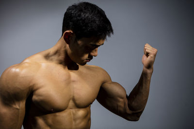 Close-up of shirtless man against gray background