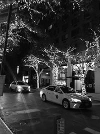 Cars on street by illuminated buildings in city at night