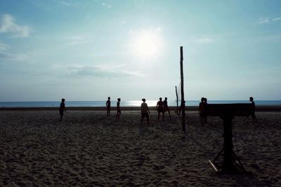 Silhouette people on beach against sky