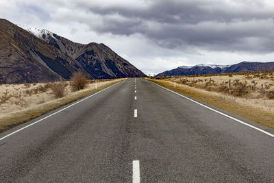 Road leading towards mountains against sky