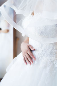 Midsection of bride wearing wedding dress