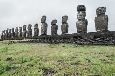 Statues on field against sky