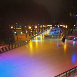 Light trails on bridge in city against sky at night