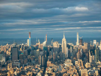 Aerial view of buildings in city against cloudy sky