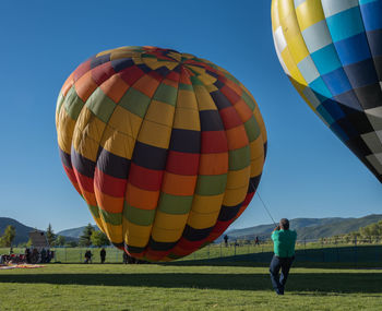 Rear view of hot air balloon flying over field