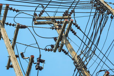 Low angle view of electricity pylon against clear blue sky