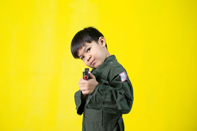 Portrait of boy standing against yellow background