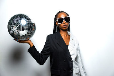 Woman wearing sunglasses standing against white background