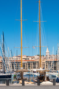 Sailboats moored at harbor against clear blue sky