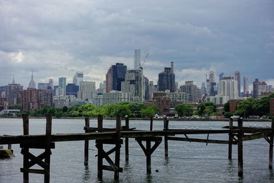 Modern buildings by river against sky in city