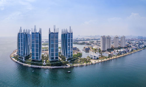 Aerial view of city at waterfront against cloudy sky
