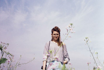 Portrait of smiling young woman standing against sky