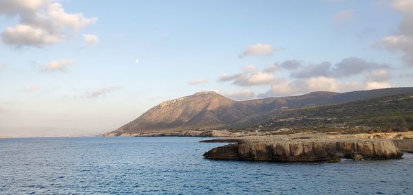 Scenic view of sea by mountains against sky