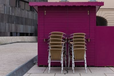 Stack of empty chairs against building