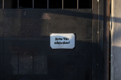 Close-up of information sign on metallic gate