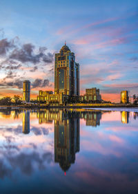 Reflection of modern buildings in lake during sunset