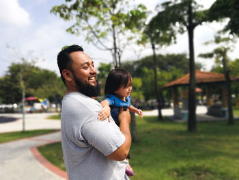 Father and son standing on daughter outdoors