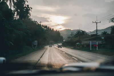 Cars on road against sky seen through windshield