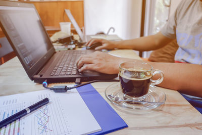 Midsection of woman using laptop on table