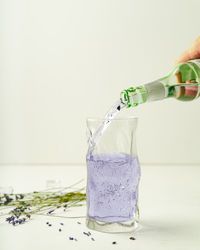 Hand holding glass bottle against white background