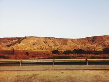 Scenic view of road amidst field against clear sky