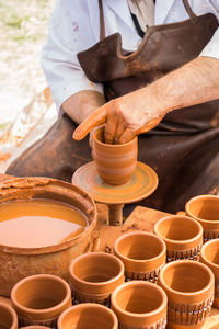 Midsection of man making clay pot at market