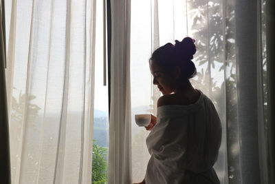 Side view of man drinking coffee in window