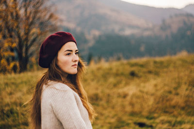 Portrait of young woman standing against mountain