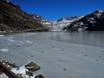 Scenic view of frozen lake by mountains against clear sky