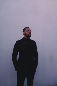 Young man looking away against wall